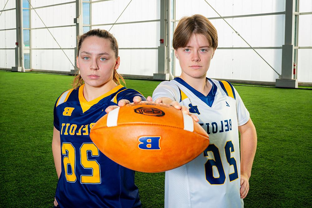 Beloit College students model the new Flag Football uniforms, holding a football together.